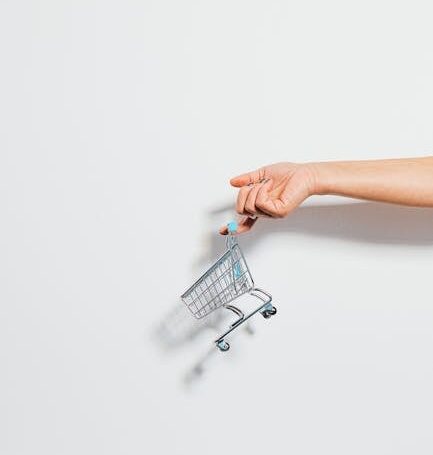 A hand holding a miniature shopping cart against a clean white background, emphasizing simplicity.